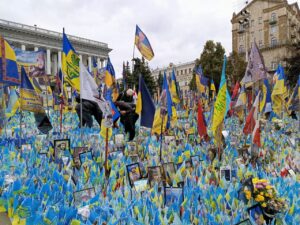 Memorial consisting of Ukrainian flags, flowers, and photographs at Maidan Nezalezhnosti, Kyiv, 2025.