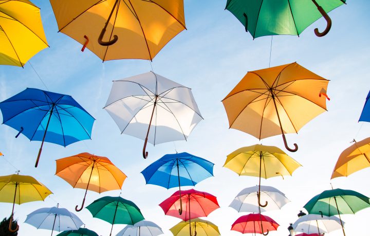 Värikkäitä sateenvarjoja sinisellä taivaalla