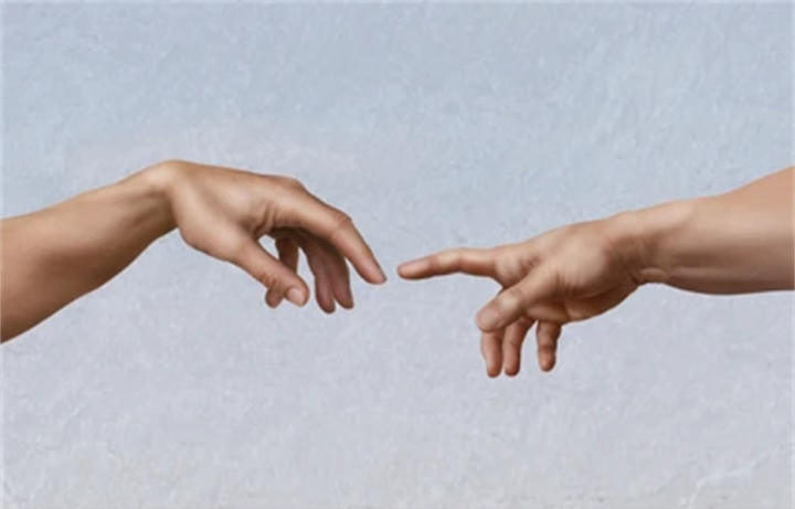 Kaksi kättä joiden sormenpäät melkein koskettavat toisiaan.