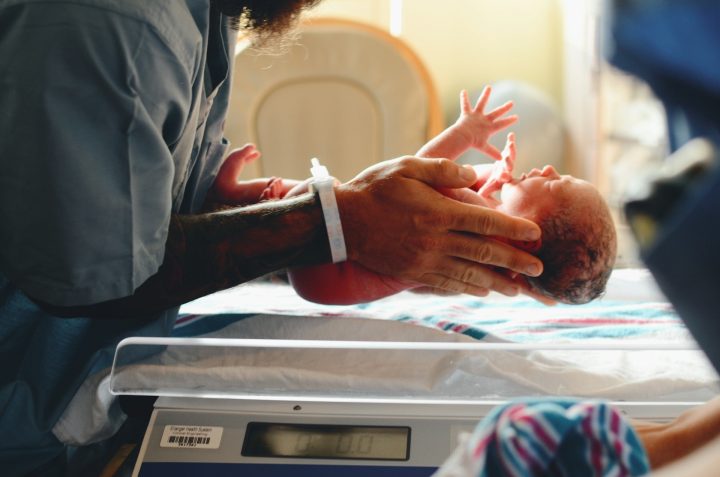 Ihminen pitää vastasyntynyttä lasta käsissään sairaalassa.