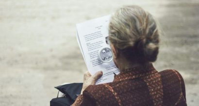 An older person reading a print with a magnifying glass.