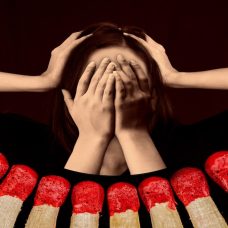 Keskellä kuvaa on pää, jonka kasvot on peitetty käsillä ja pään molemmilla puolin on toiset kädet. Hahmoa ympäröivät tulitikut.