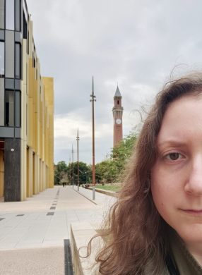 Photo of Aino Liira, partial face view, with the University of Birmingham Main Library and Old Joe in the background.