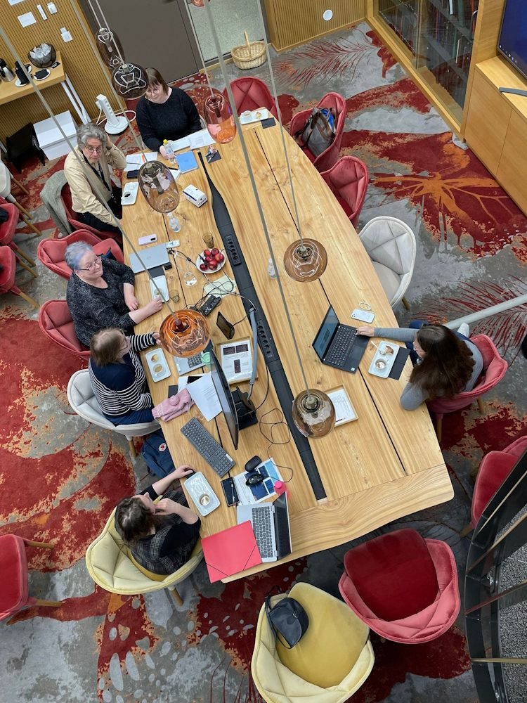 Photo of the workshop participants gathered around a table in the meeting room Luoma in Arcanum.