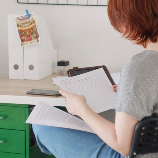 Nainen selaa pöydän ääressä papereita