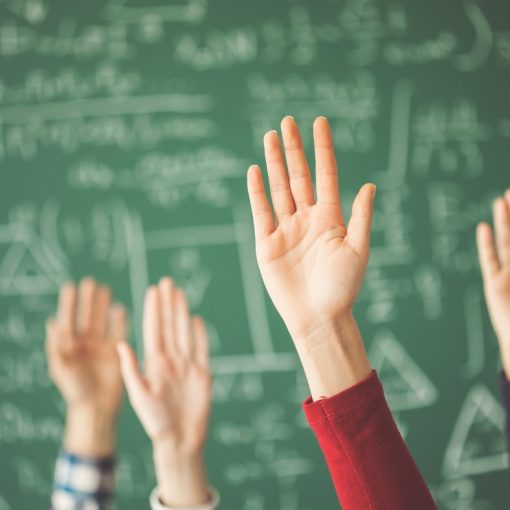 Viittaavia käsiä liitutaulun edessä