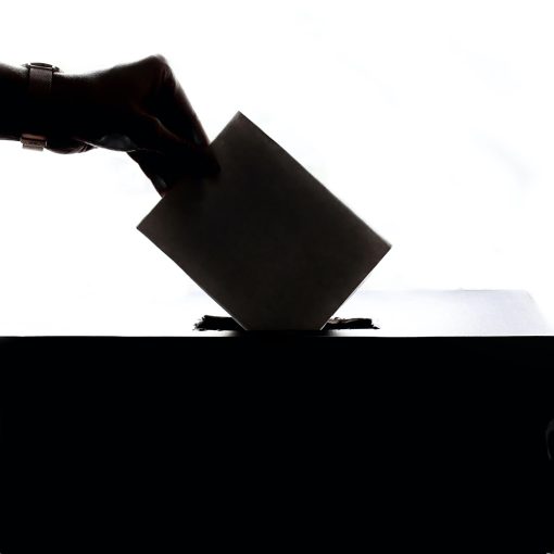 A hand dropping a vote envelope into a box