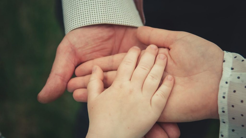 kahden aikuisen ja lapsen kädet päällekkäin