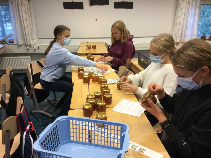 Koululaiset tarrottavat hunajapurkkia.