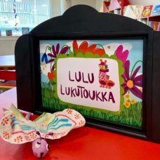 Perhosjuhlien värikäs koriste, jossa lukee "Lulu lukutoukka".