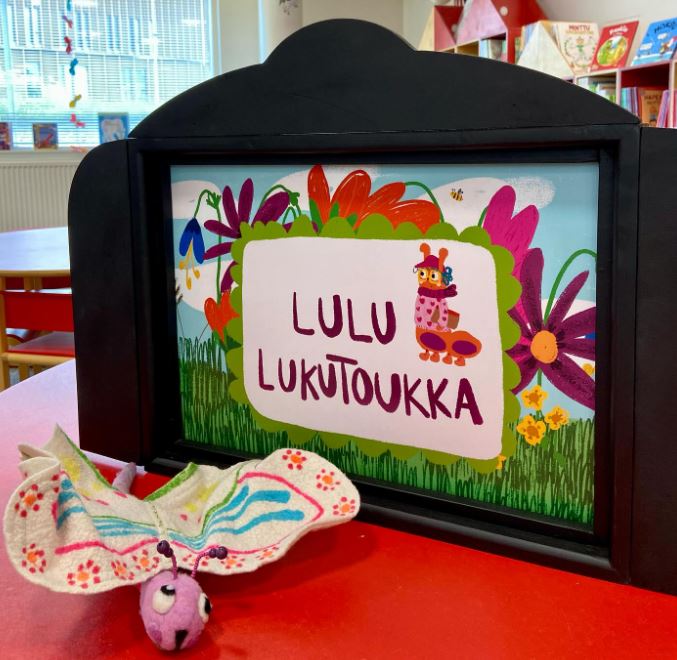 Perhosjuhlien värikäs koriste, jossa lukee "Lulu lukutoukka".