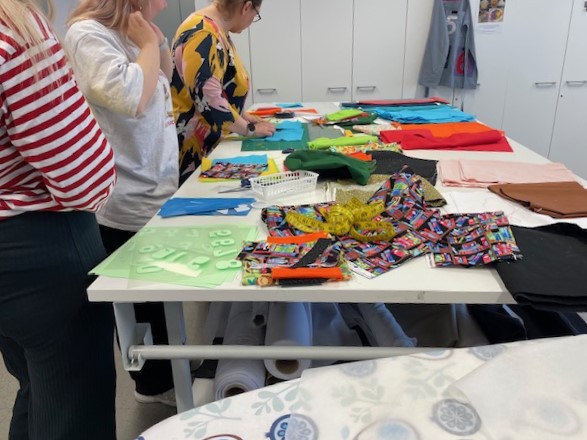 Ihmiset tekevät käsitöitä kankaista pöydän ääressä.