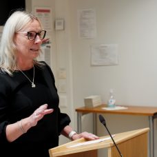 Nainen pitää puhetta puhujakorokkeella.