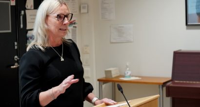 Nainen pitää puhetta puhujakorokkeella.