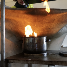 Pelastaja sammuttaa sammutuspeitolla liekehtivää kattilaa.