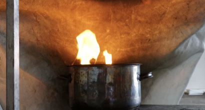 Pelastaja sammuttaa sammutuspeitolla liekehtivää kattilaa.