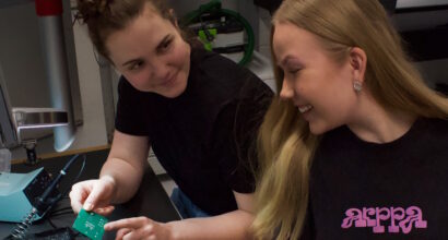 Kaksi ihmistä tekevät juottotyötä pöydän ääressä.