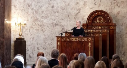 Nainen pitää puhetta juhlasalissa.
