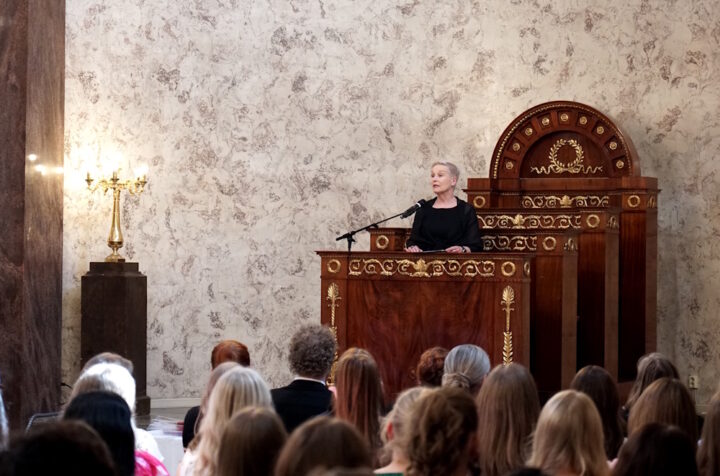 Nainen pitää puhetta juhlasalissa.