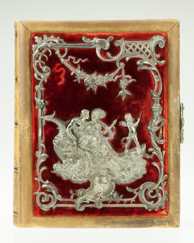 Nahkainen albumi kannessaan punaista samettia, minkä päällä on metallinen koristekuvio.