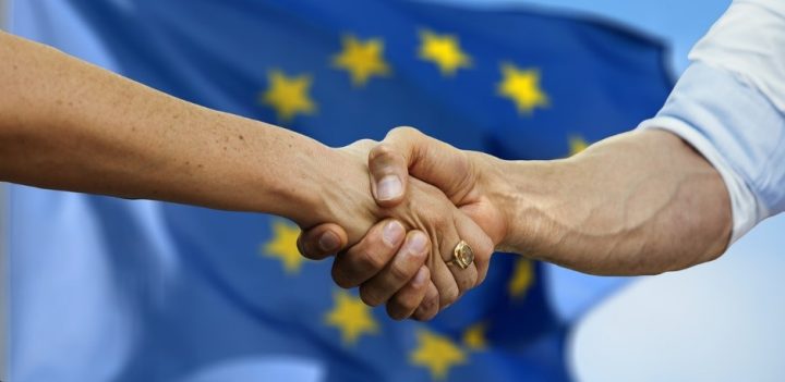 Kädenpuristus EU-lipun edessä.