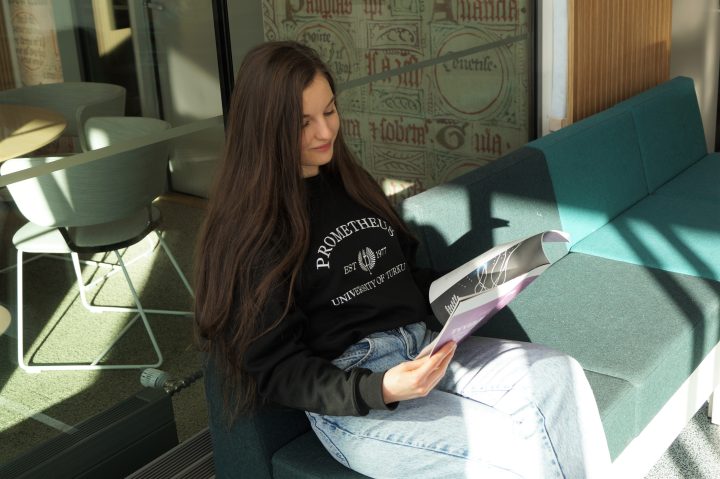 Turun yliopistossa kahta tutkintoa suorittava opiskelija lukee lehteä kampuksen sohvalla.