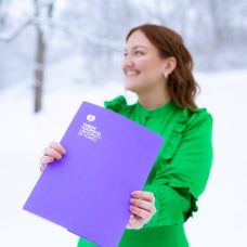 Oikeustieteen maisteri Emma Karttunen, joka pitää kädessään Turun yliopiston todistuskansiota.