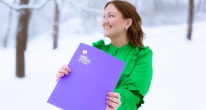 Oikeustieteen maisteri Emma Karttunen, joka pitää kädessään Turun yliopiston todistuskansiota.