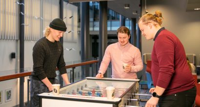 Kolme opiskelijaa pelaa pöytäjalkapalloa Turun kauppakorkeakoululla.