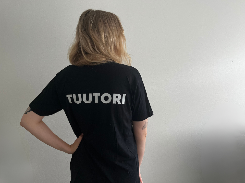 henkilö takaapäin kuvattuna, paidassa lukee tuutori