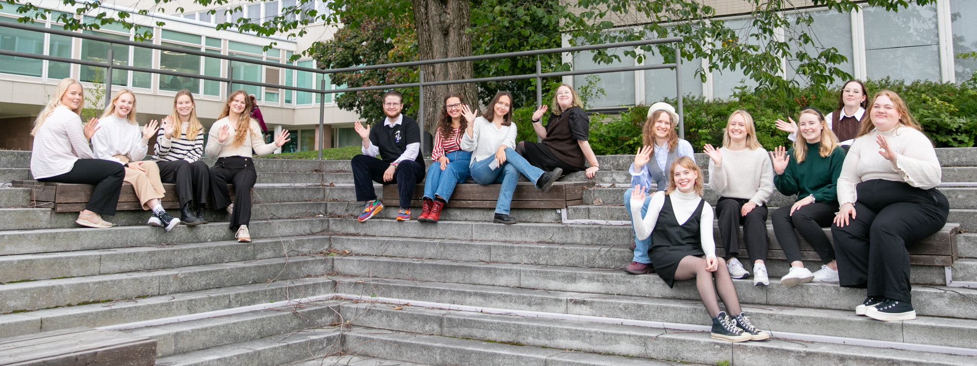 Opiskelijalähettiläät yliopistonmäellä istumassa pääaukion portailla.