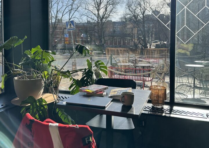 Kuva opiskelijakahvilasta Kulmasta, jossa opiskelijan kannettava tietokone, opiskelutarvikkeet ja kahvikuppi