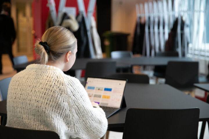 Opiskelija opiskelemassa läppärillä yliopiston aulatiloissa.