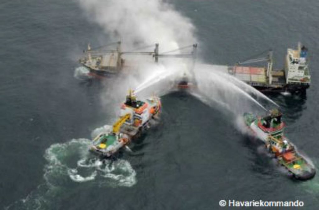 Two emergency response ships dousing the cargo vessel MV Purple Beach with water due to overheated and smoking fertilizer cargo in the middle of the North Sea.