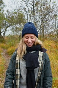 Image showing a smiling person dressed in warm outdoor clothes in an autumn setting.