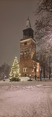 Image showing the Turku Cathedral covered in a thick layer of snow, with a big Christmas tree in front if it.