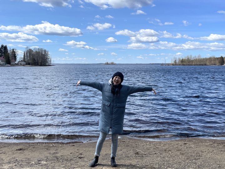 Writer Hinako Matsui standing in front of a beautiful lake and smiling