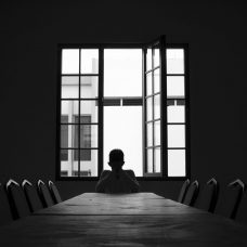 Henkilö istuu yksin tyhjässä kokoushuoneessa