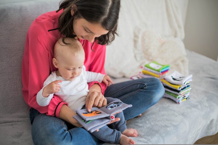 Vanhempi selaa vauvan kanssa kirjaa.